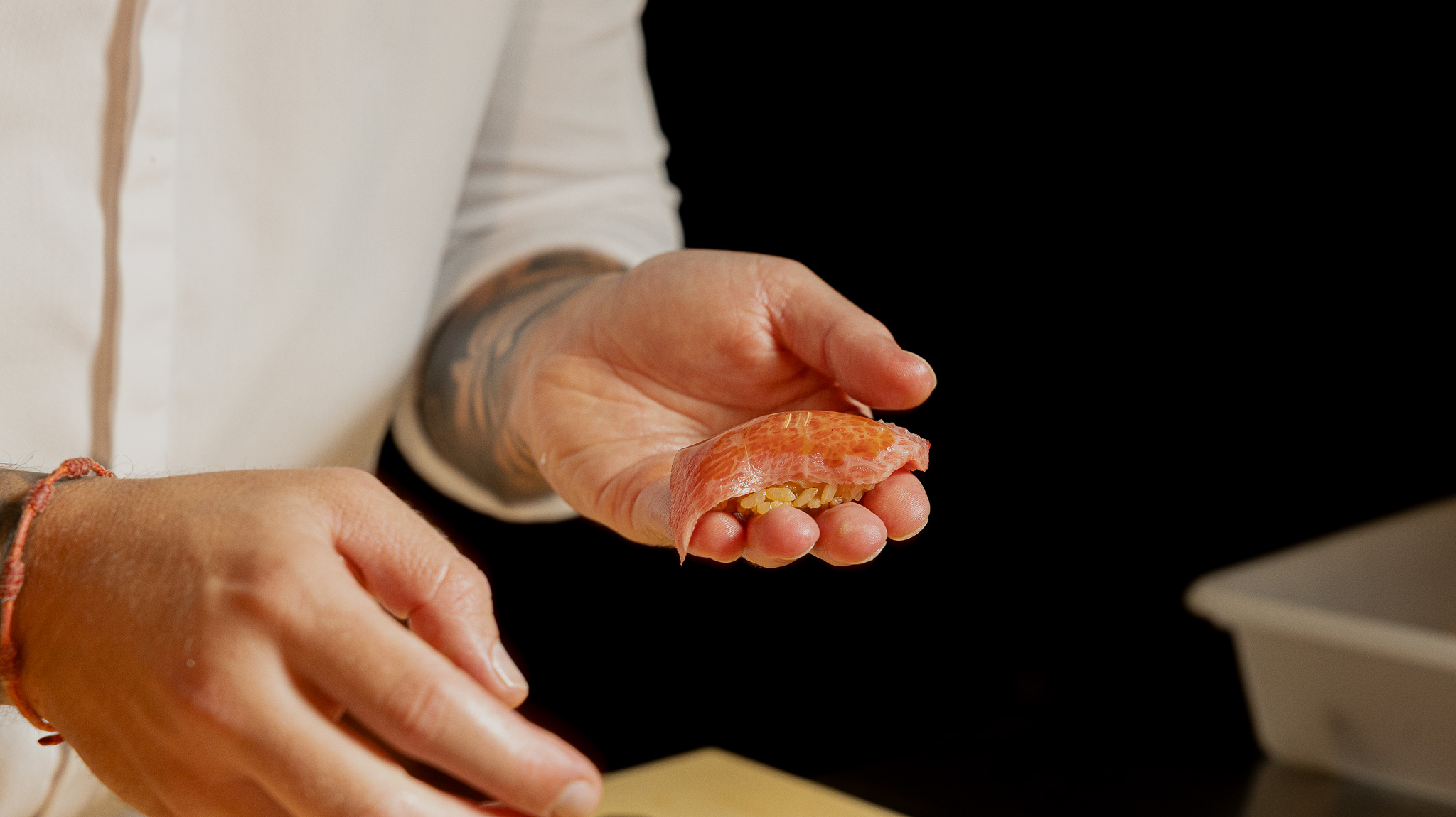Las manos del chef presentan un nigiri en Nakara